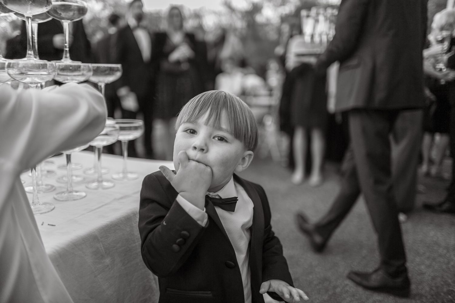 Champagne tower being assembled with coupe glasses at an outdoor celebration.