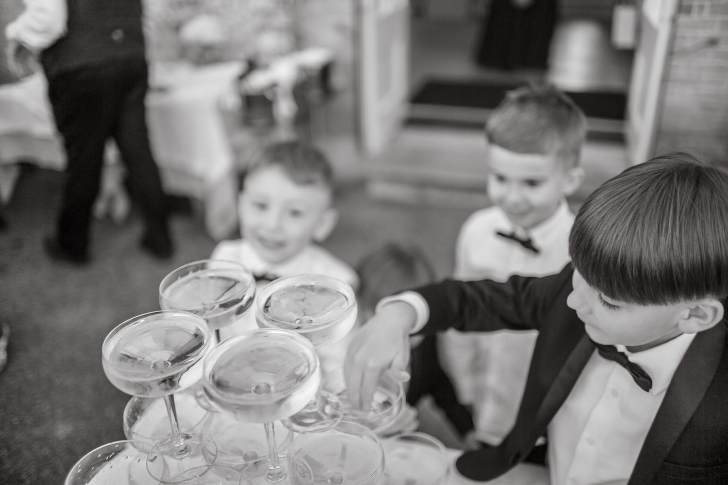 Young guest in formal wear reaches for a glass from the champagne tower display.