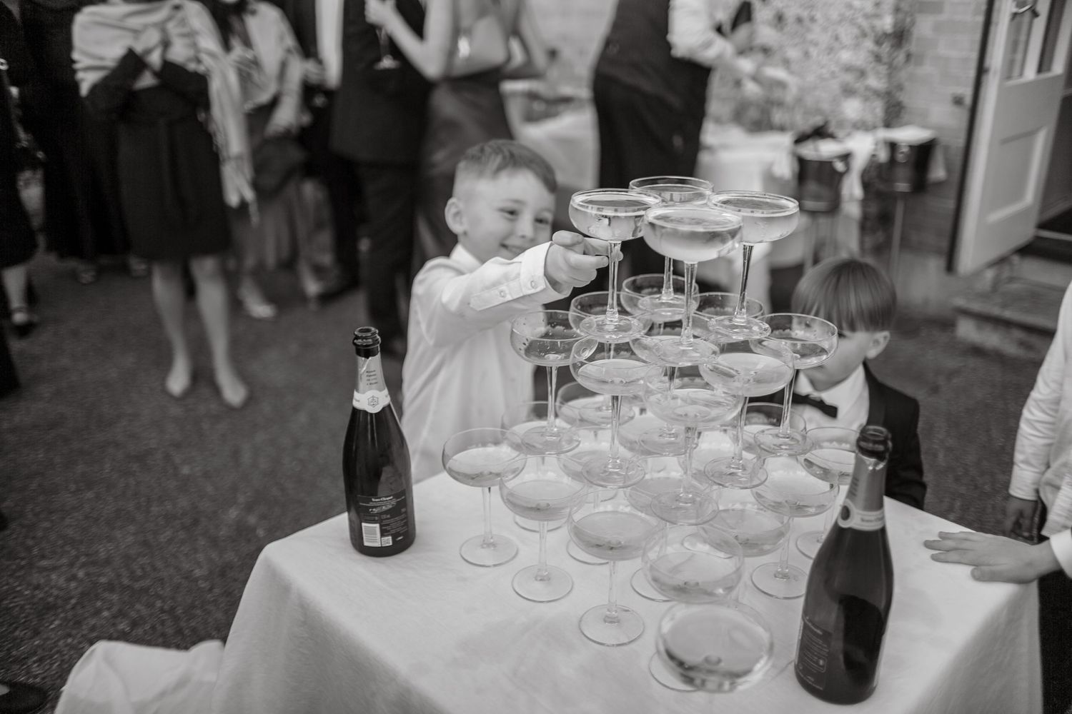 Elegant champagne tower setup with coupe glasses at an outdoor wedding reception.