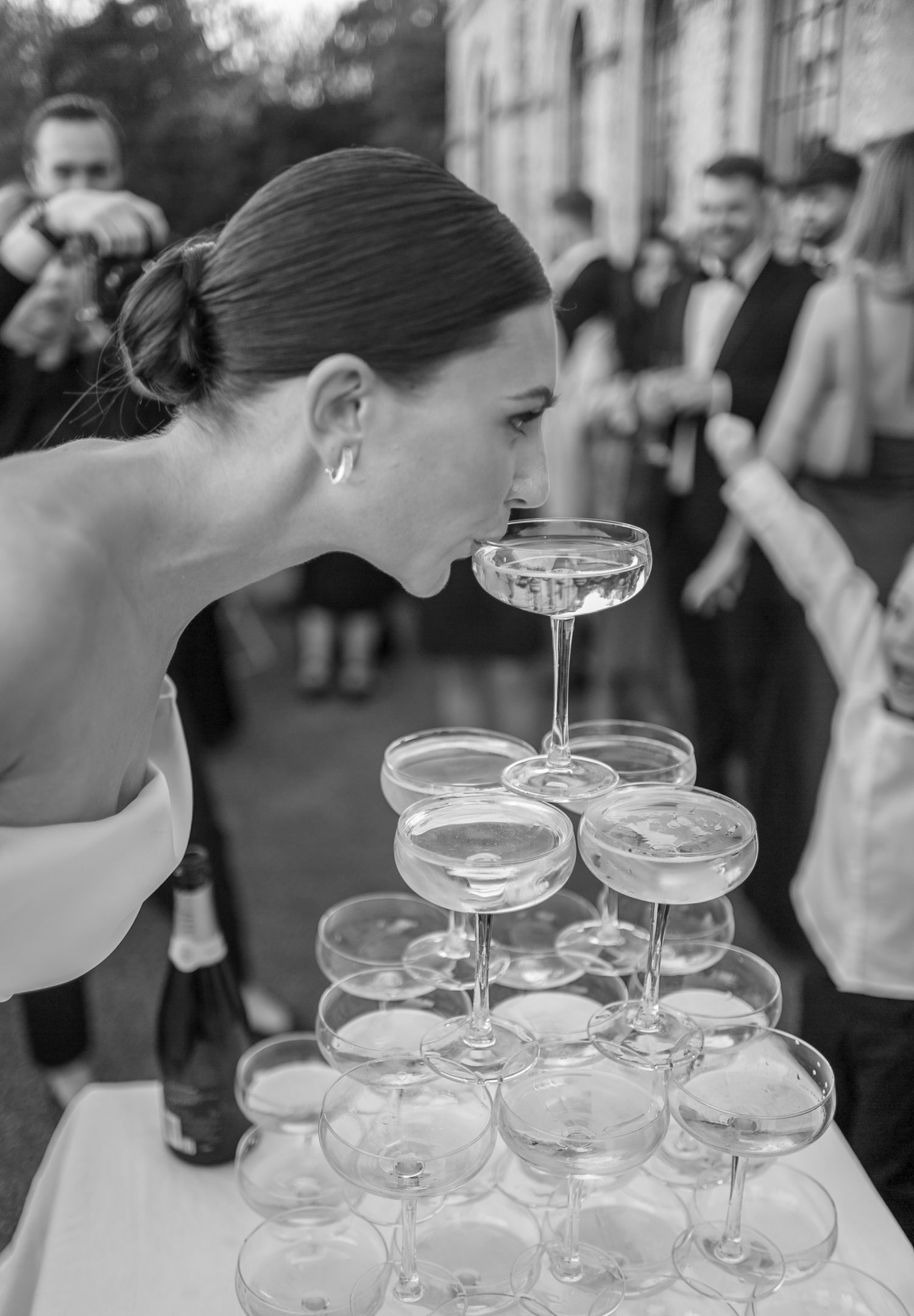Crystal champagne coupes arranged in tiers as guests gather for the pouring ceremony.