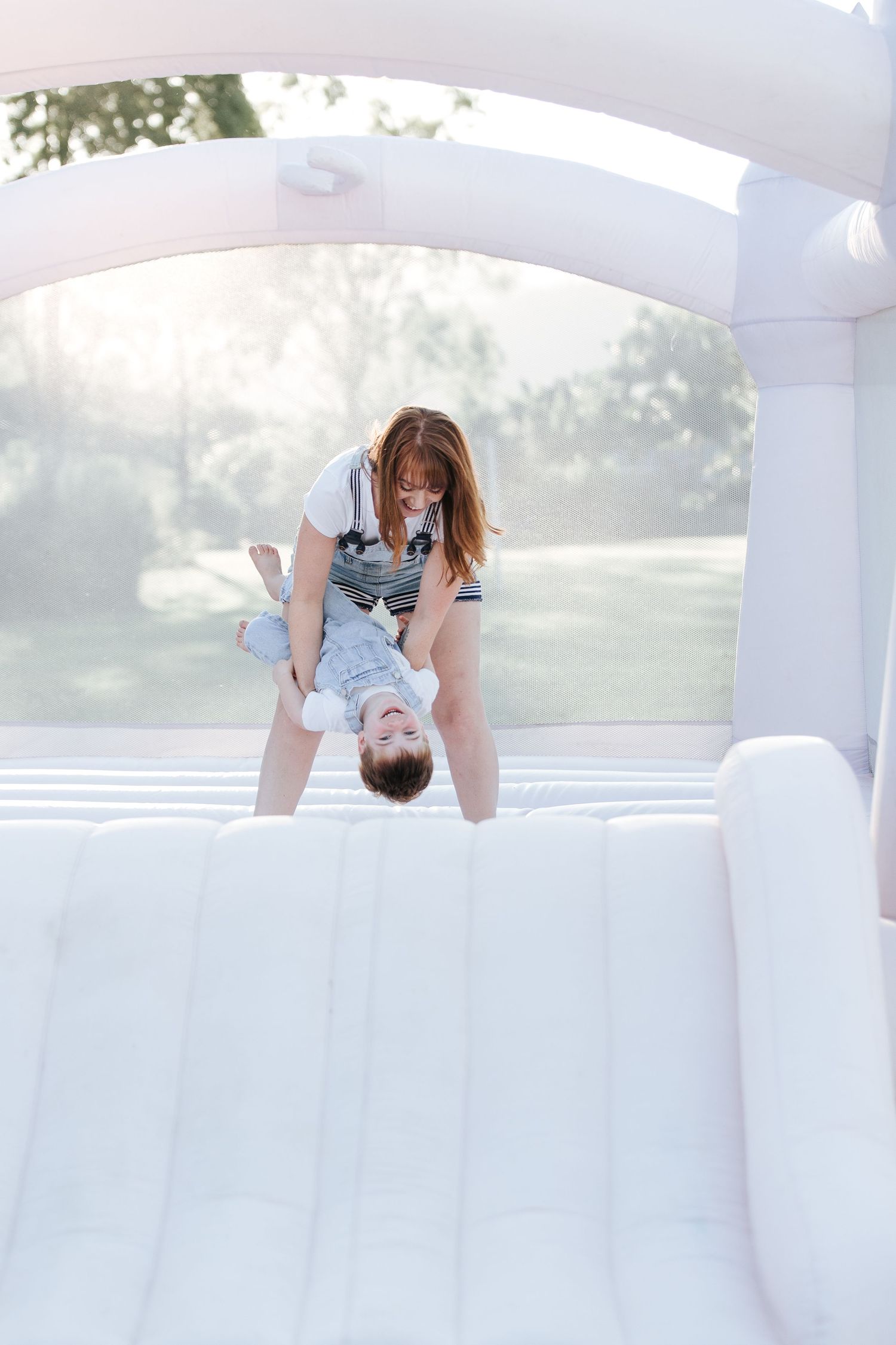 Energetic play session in a bright white bounce castle with arched windows.