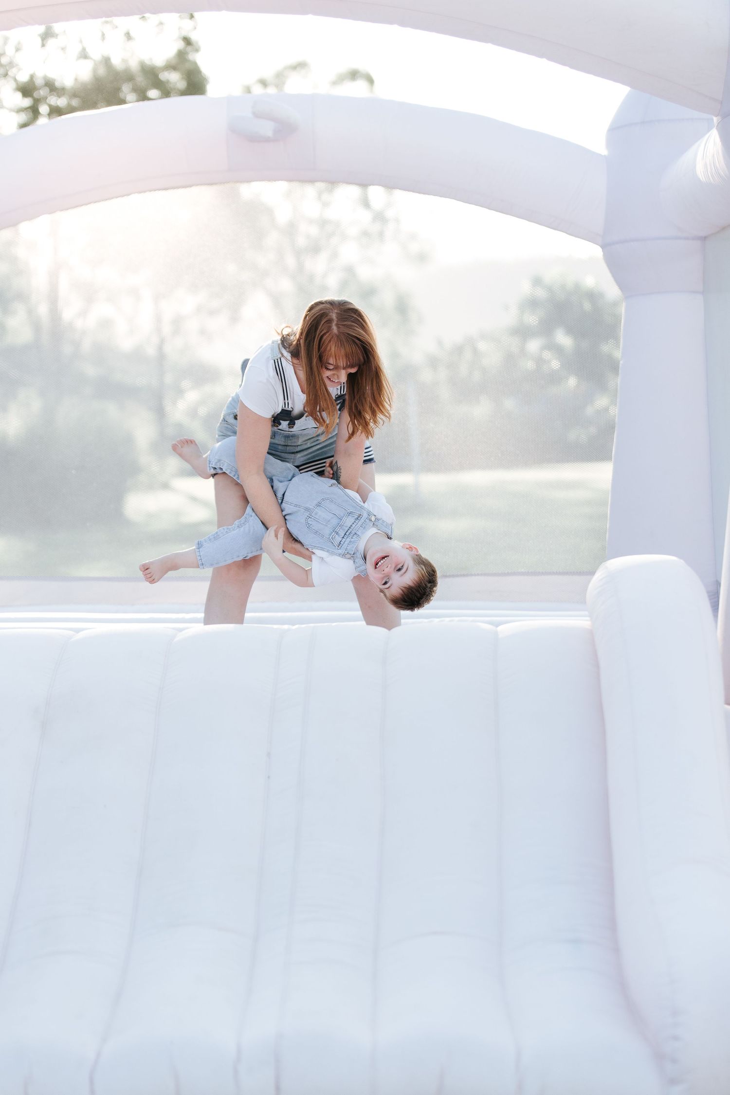 Joyful playtime in an all-white inflatable bounce house on a sunny day.