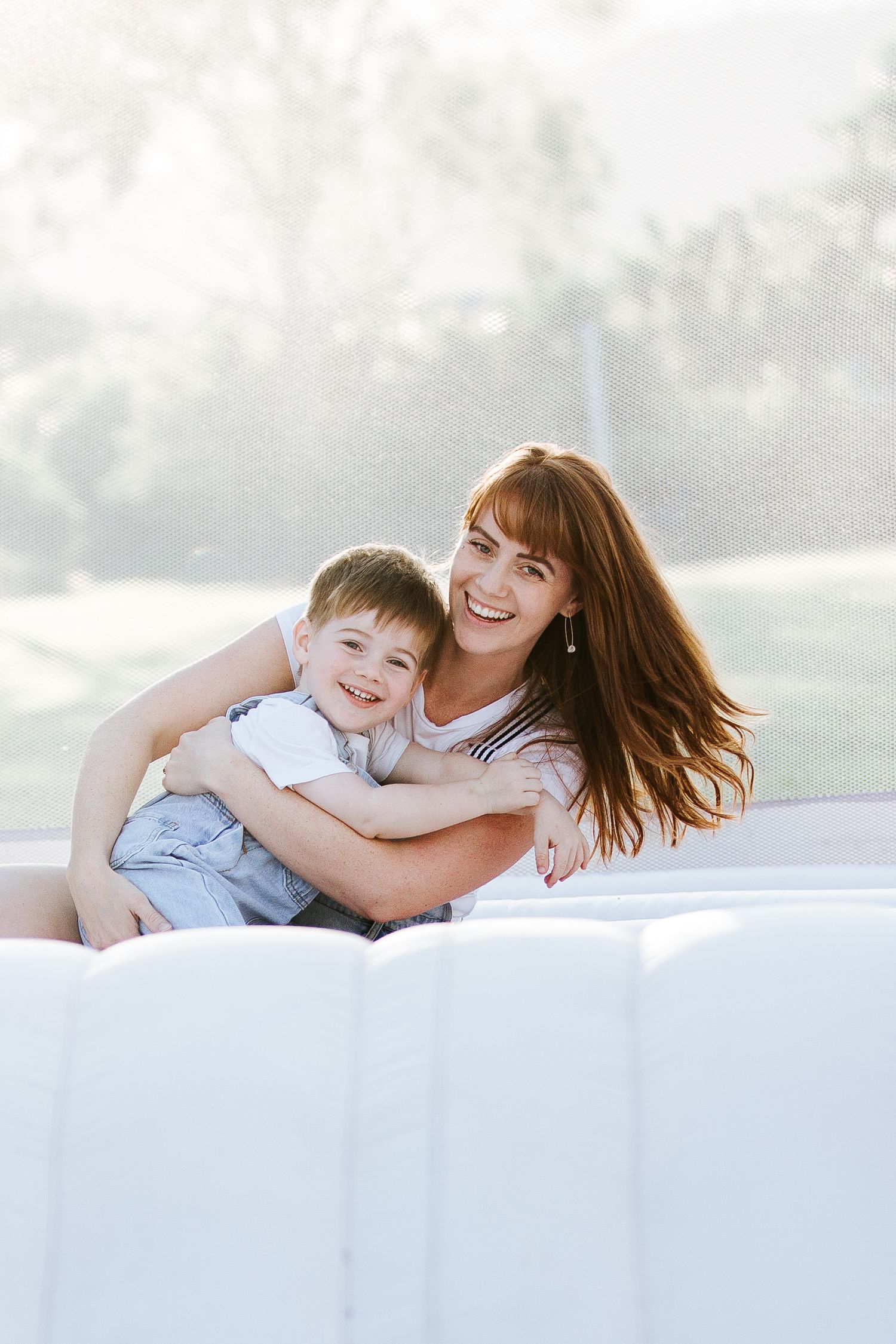Sweet candid moment shared in a white inflatable bounce house during an outdoor photo session.