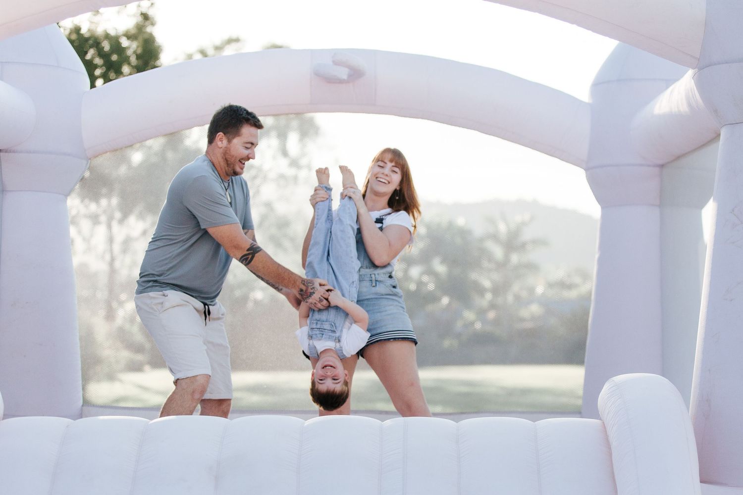Active playtime captured in a white inflatable bounce house during an outdoor photo session.