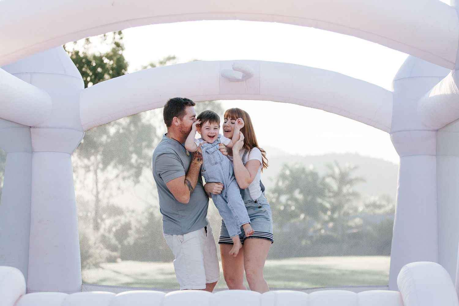 Happy family moment shared in a white castle-themed bounce house on a sunny afternoon.