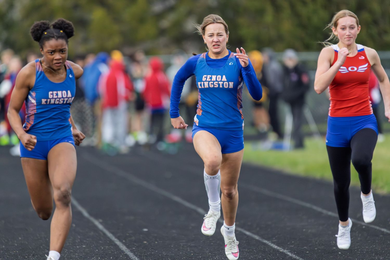 Track athletes sprint down lanes during competitive race on outdoor track.