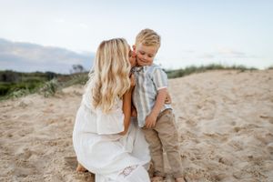 A tender moment captured on a sandy hill during golden hour.