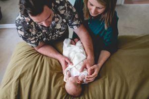 Parents sharing a tender moment with their newborn on bed.