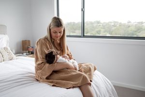 Peaceful moment by window as parent cradles newborn in cozy bedroom setting.