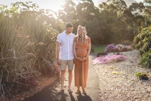 Couple standing on garden path during golden hour sunset.