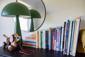 Green vintage desk lamps and children's books arranged on a dark wooden surface.