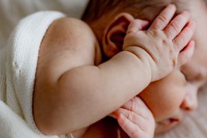 Close up of baby's hand touching face while resting.