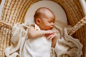 Baby sleeps peacefully in a woven basket lined with soft textured fabrics.