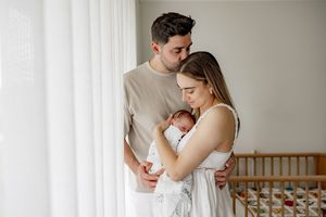 Loving parents sharing tender moments with their newborn baby in a bright, airy nursery setting.