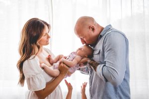 Parents sharing a joyful moment with their baby near bright windows.