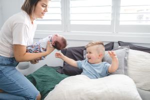 Family playing and laughing together on a cozy white bed.