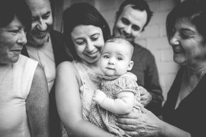 A group of family members gather around a baby in a black and white photograph.