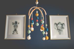 Colorful nursery mobile hanging above with framed artwork in background.