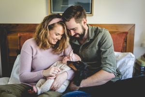 A couple sharing a tender moment with their newborn baby on a couch.