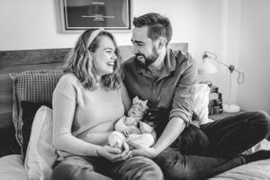 Intimate black and white portrait of new parents sharing a joyful moment together.