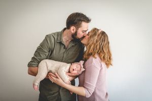 Family sharing an intimate moment together against a neutral background.