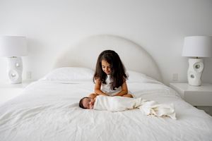 A person sleeps peacefully in white bedding with matching pillows and blankets in a minimalist bedroom setting.