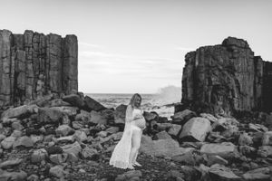 Black and white portrait on dramatic rocky cliffs with columnar rock formations and ocean backdrop.