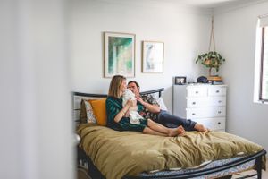 Family relaxing together on bed in bright, modern bedroom.