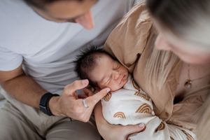 Intimate family moment captured in soft natural light on white bedding.