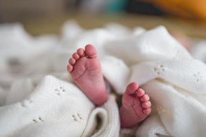 Close-up of tiny baby feet against white textured fabric.