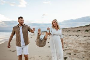 A family shares a playful moment together on a beach at sunset.