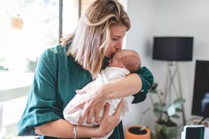 Tender moment with a newborn being held in gentle embrace.