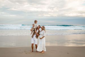 A family enjoys a tender moment together on a scenic beach at sunset.
