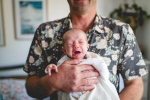 Emotional moment with crying newborn being comforted and held.