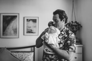 Intimate black and white portrait of newborn being cradled.