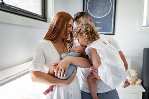Family sharing tender moment together in bright white room with modern decor.