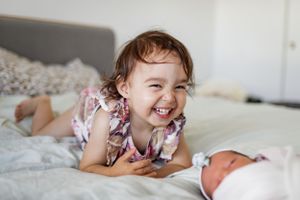 Joyful moment captured on a cozy bed with white linens.
