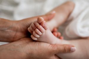 A tender close-up of tiny baby toes being held by adult hands.