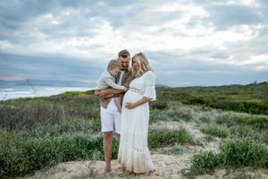 A family shares an intimate moment on a hilltop surrounded by coastal vegetation.