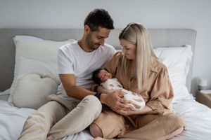 Tender family scene in a minimalist bedroom with neutral tones.
