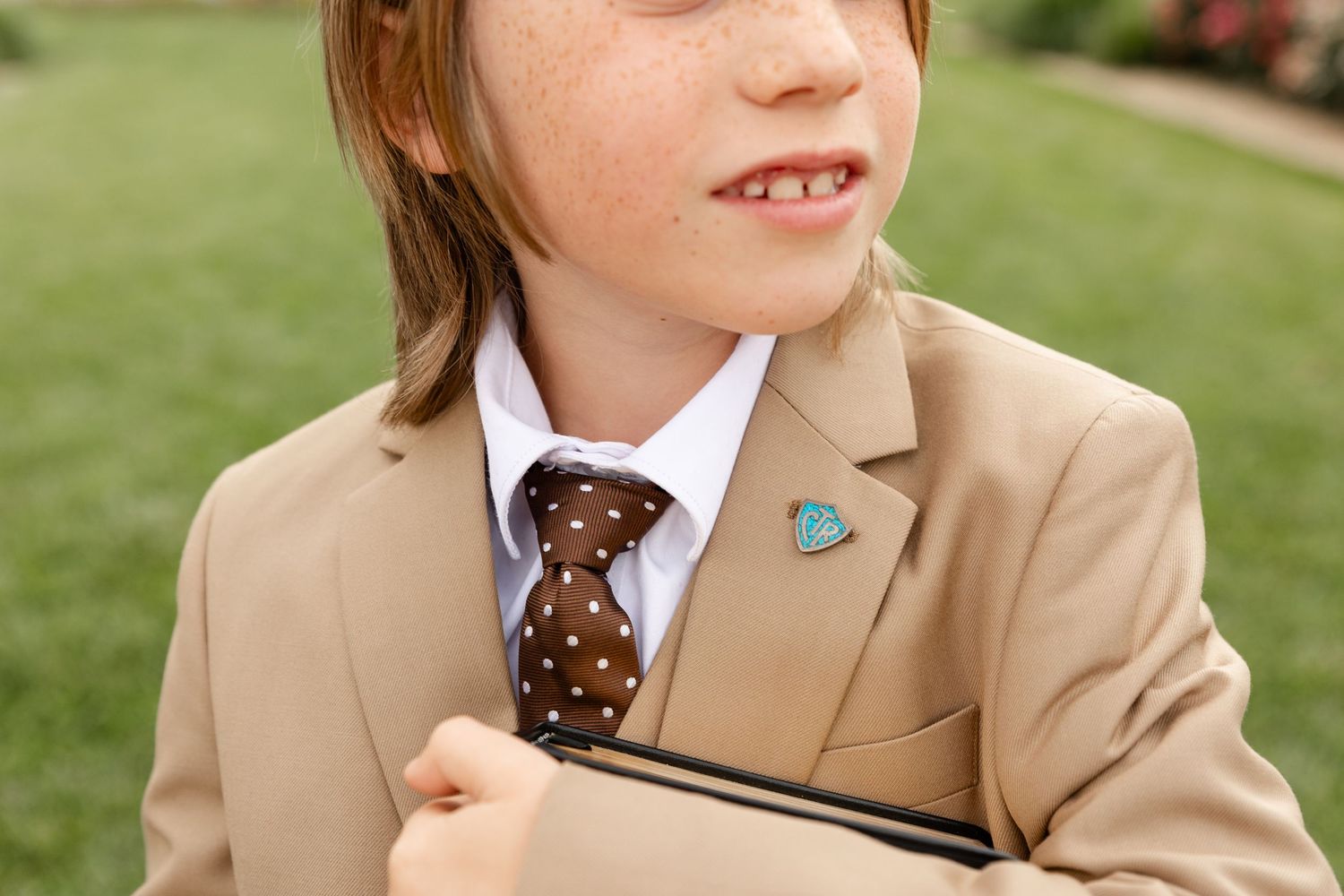 close up of a boys lapel and his CTR pin boring suit and tie white shirt