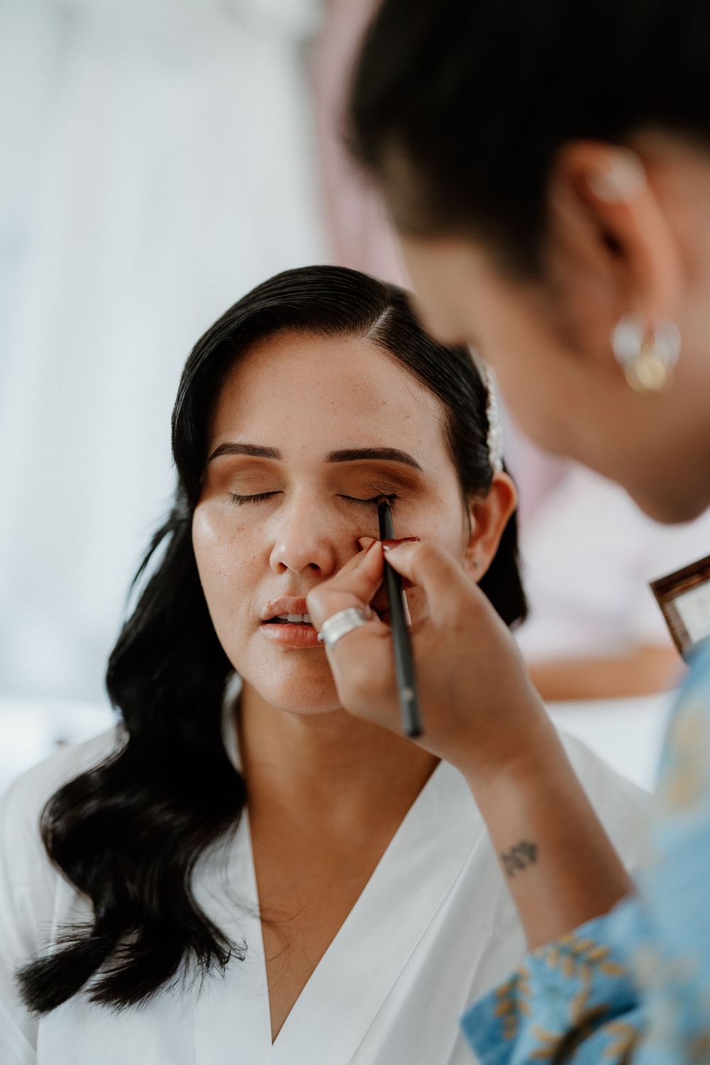 Close-up shot of wedding makeup application in a bright indoor setting.