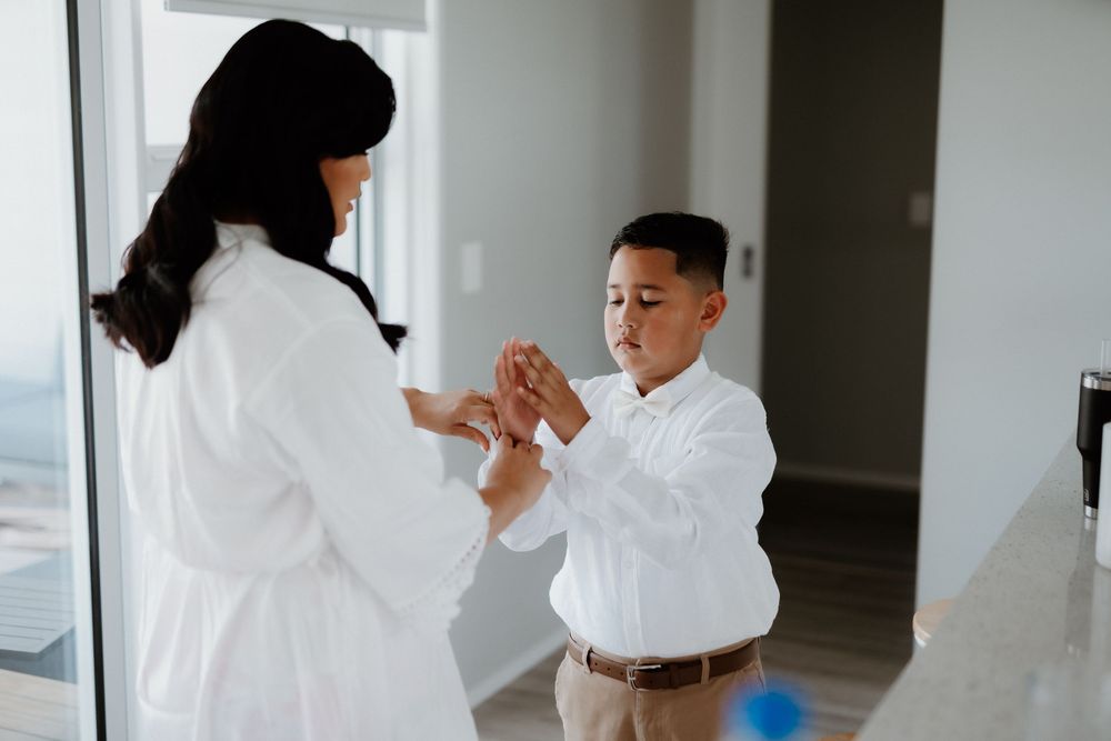 Getting ready moment in a bright room with crisp white attire.