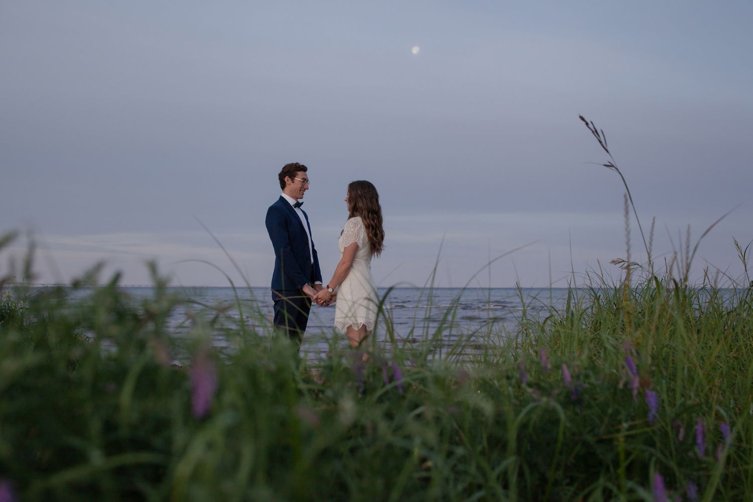 lumenali photography: couple eloping on the beach at sunrise with the moon in the background. prince edward island, canada