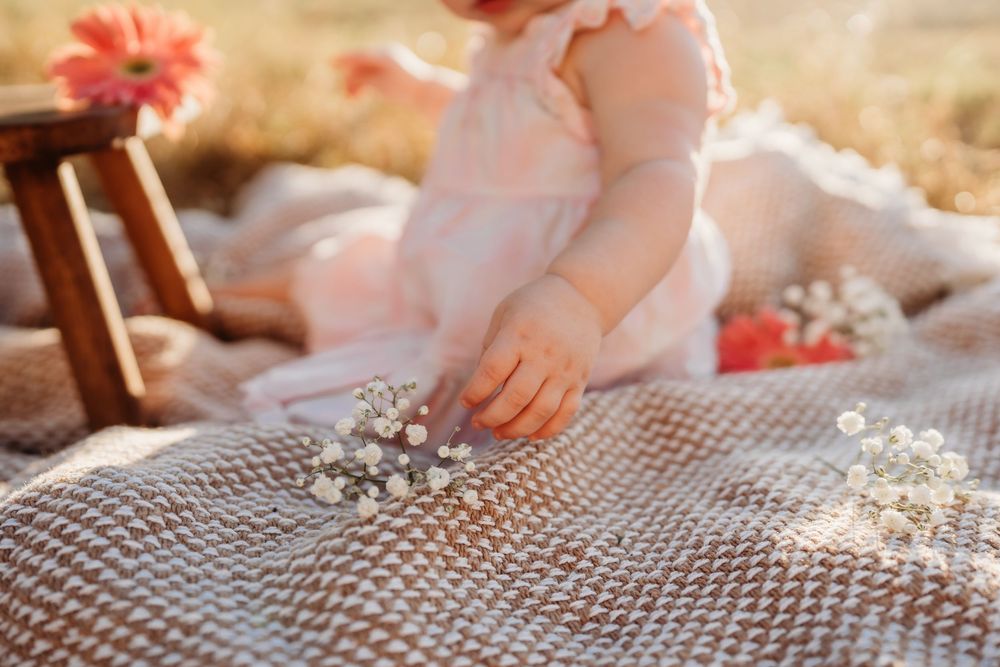 Delicate white lace blanket with small hands touching silver jewelry in warm sunlight.
