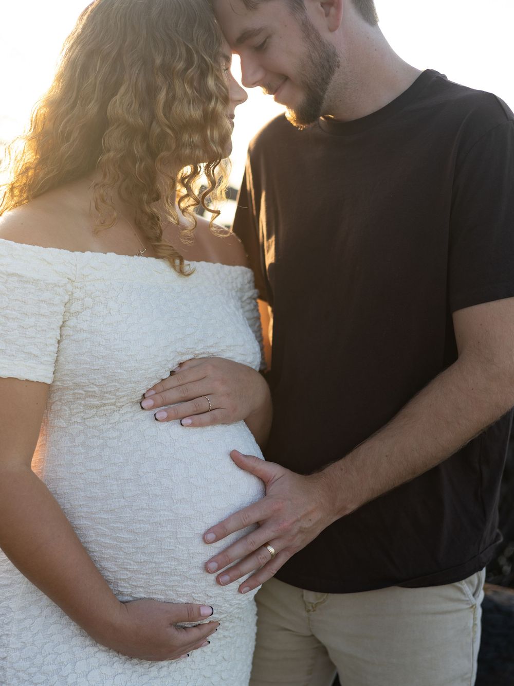 A series of tender maternity photos captures intimate moments between a couple against a natural outdoor backdrop.