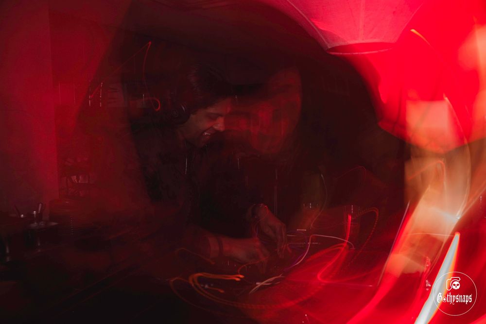 Silhouette performing at a music event with dramatic red lighting and atmospheric effects.