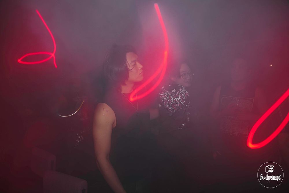 Seven red neon light fixtures create a dramatic glow effect against a dark background in a club setting.