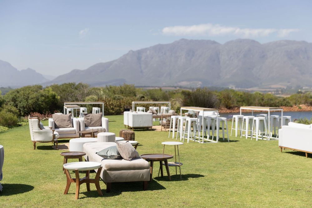 Outdoor lounge setup with white furniture and mountains in the background for an elegant event reception.