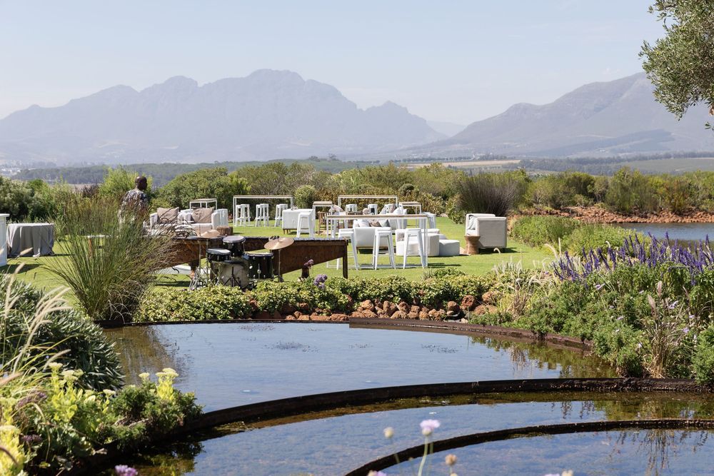 Mountain landscape view with serene pond and lush garden landscaping in the foreground.
